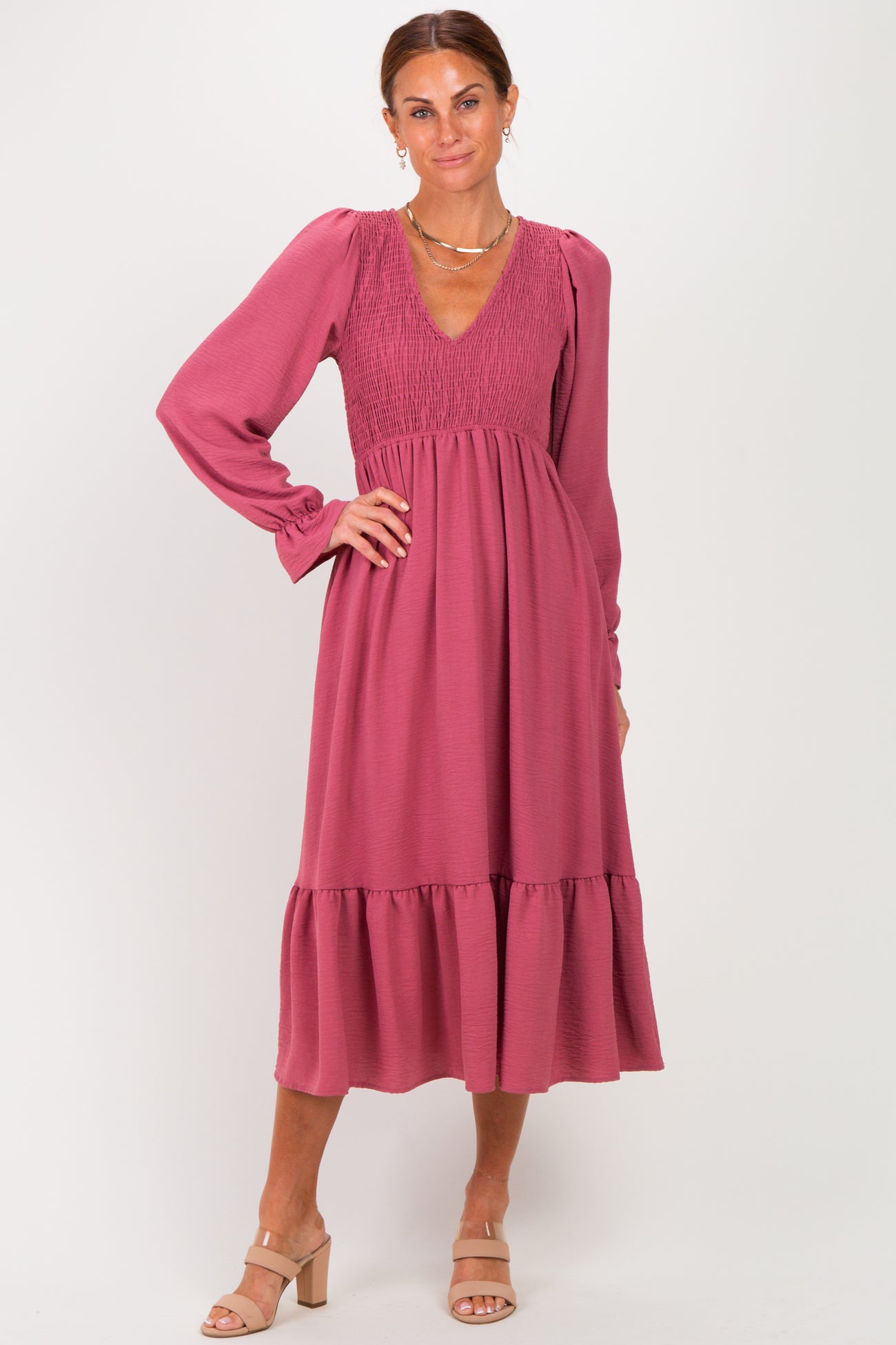 woman wearing a rose-colored long sleeve smocked dress with a tiered skirt and a V-neckline