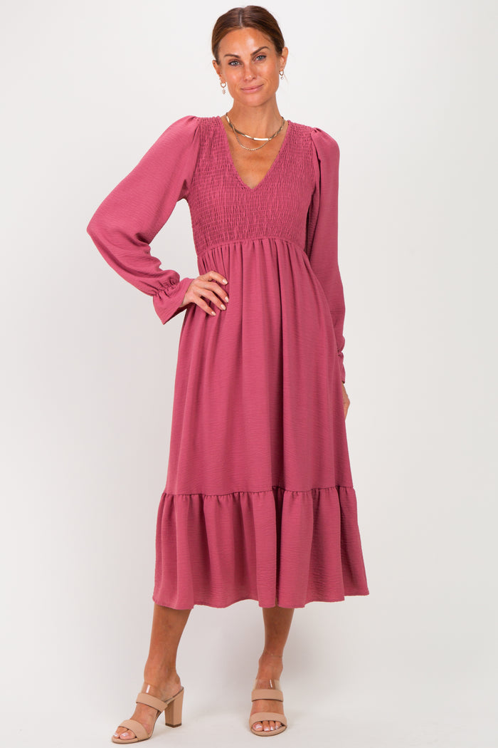 woman wearing a rose-colored long sleeve smocked dress with a tiered skirt and a V-neckline