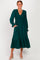 woman wearing a dark green long sleeve dress with smocked bodice and tiered skirt, posing with her hands in pockets