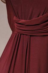 close-up of a burgundy dress featuring a gathered waist detail and pleats