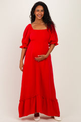 woman wearing a red maternity maxi dress with puff sleeves, holding her baby bump