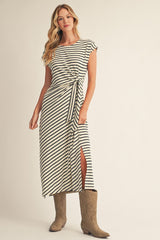 woman wearing a striped maxi dress with a tie waist and side slit, paired with brown cowboy boots