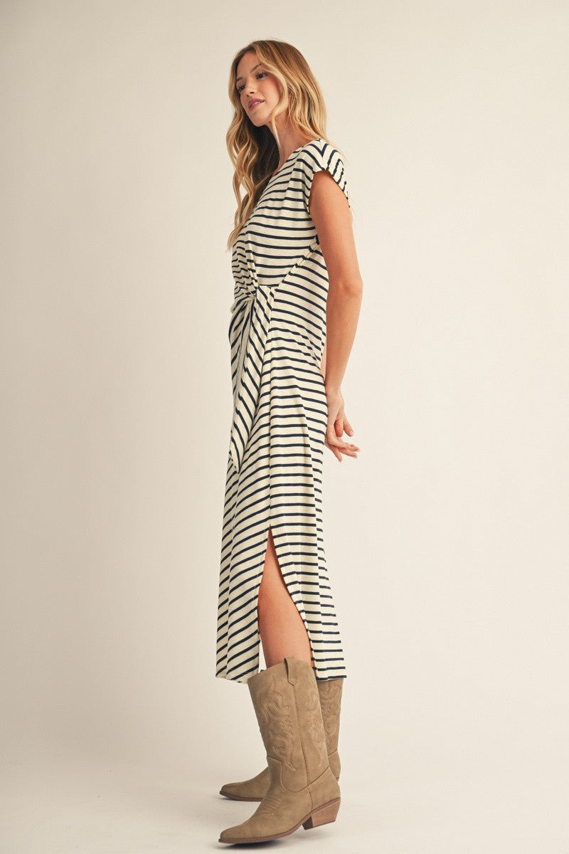 woman wearing a striped midi dress with a side slit and twist front detail, paired with taupe western boots