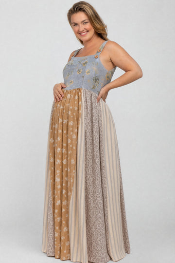 woman wearing a floral patterned maternity maxi dress with a blue top and multi-colored skirt, showing her baby bump