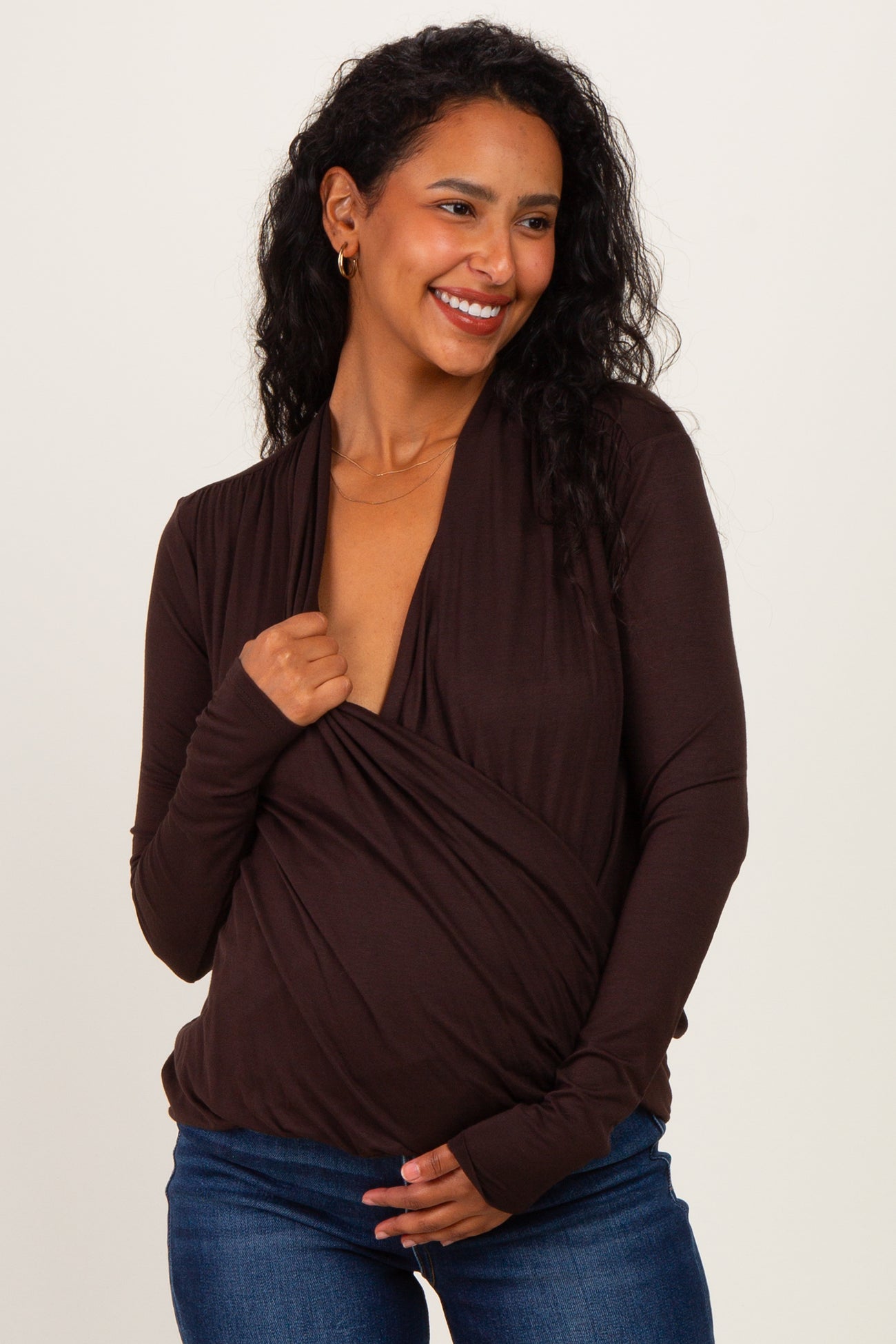 woman wearing a brown maternity wrap top with a deep v-neck and a relaxed fit, showing her baby bump