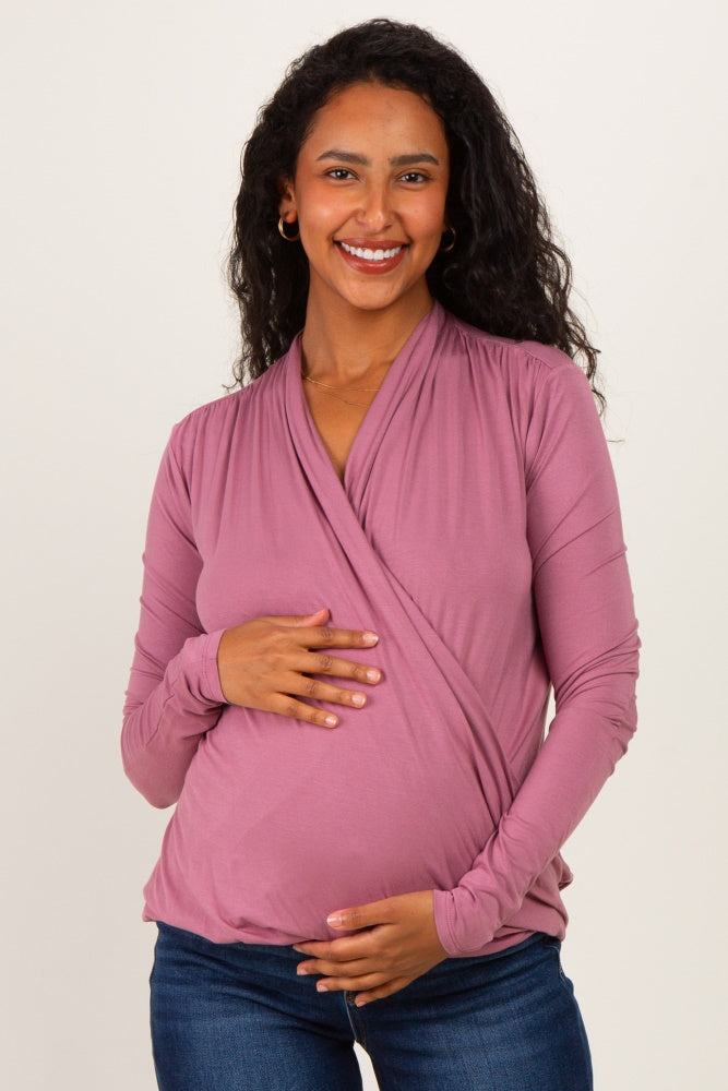 woman wearing a mauve wrap maternity top and holding her baby bump