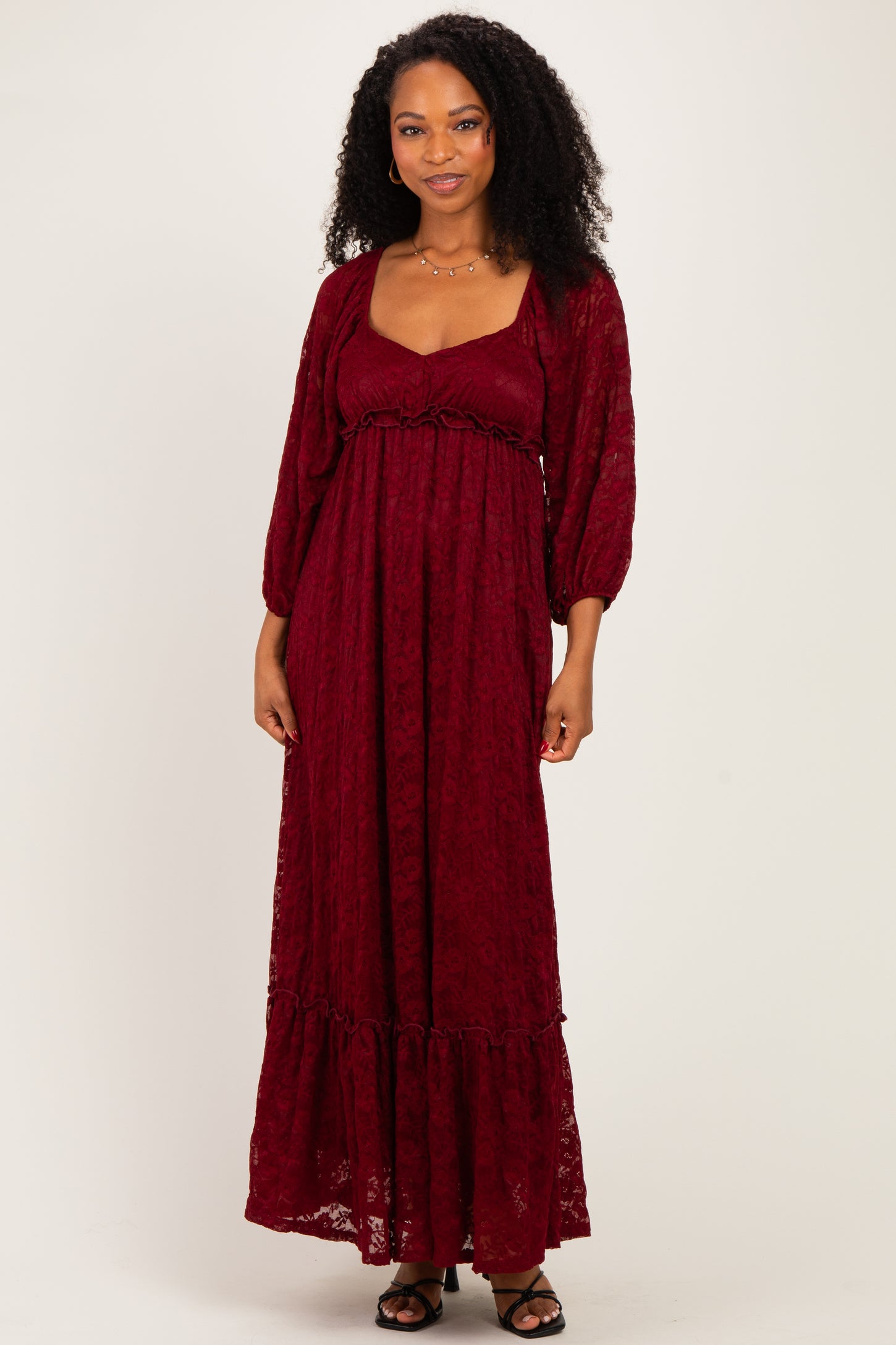 woman wearing a burgundy long sleeve lace maxi dress with a square neckline and ruffle hem