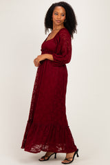 woman wearing a burgundy lace maxi dress with a ruffled hem and puffy sleeves