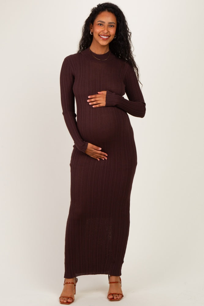 woman wearing a brown ribbed maternity dress, holding her baby bump with a smile