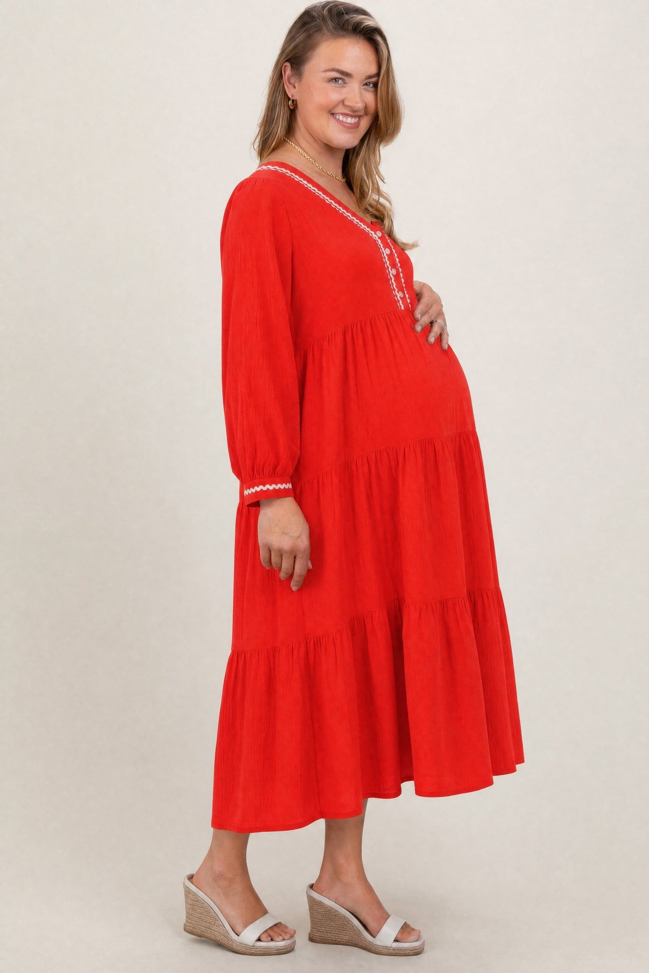 woman wearing a red tiered maternity maxi dress with embroidery and a visible baby bump