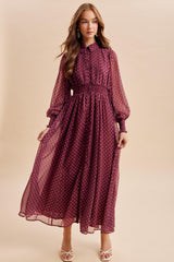 woman wearing a burgundy polka dot maxi dress with a cinched waist and puff sleeves