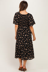 woman wearing a black floral maternity dress with a smocked bodice and tiered skirt, seen from the back