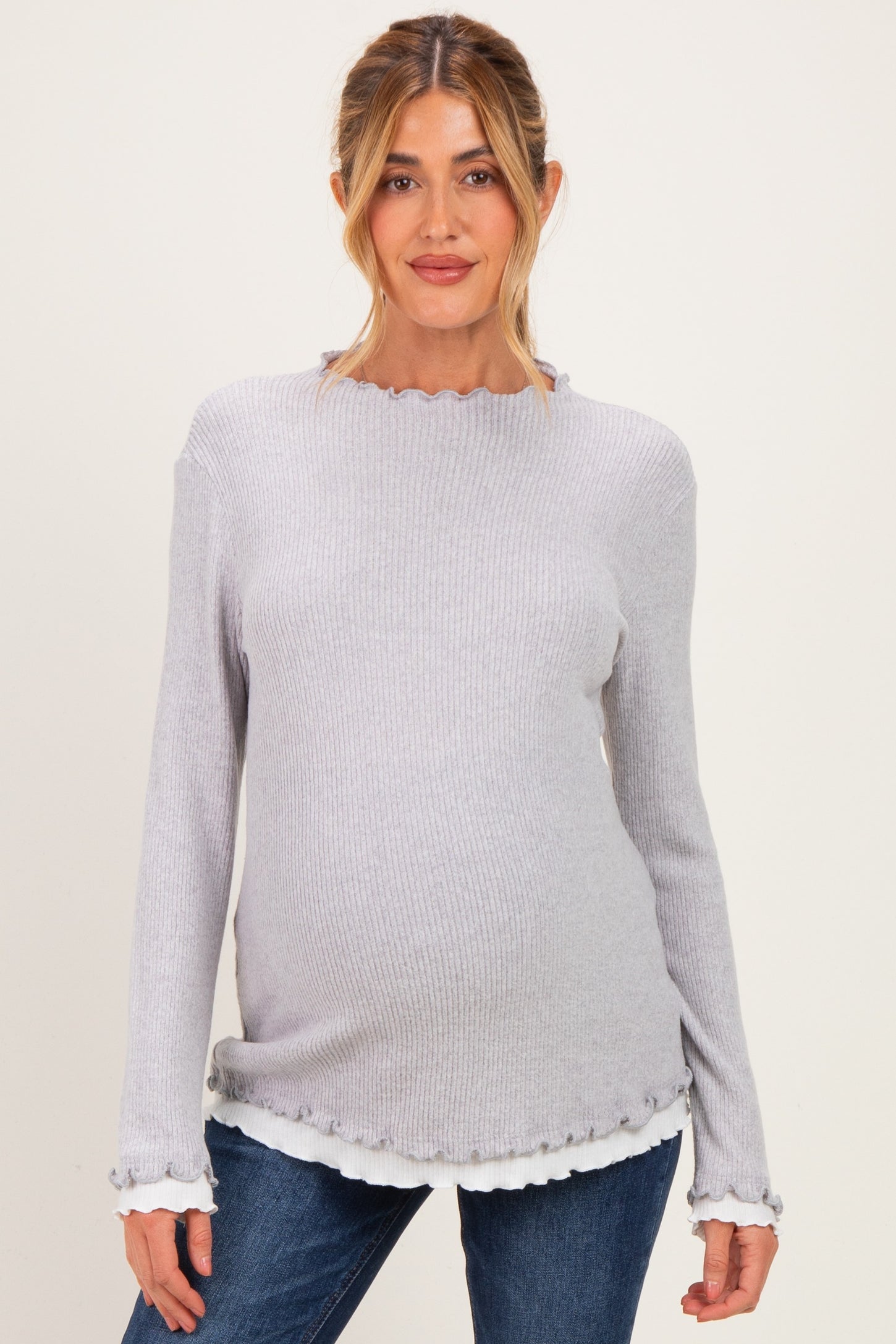 woman wearing a gray ribbed maternity top with ruffled cuffs and a visible baby bump