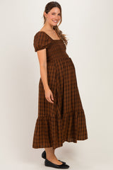 woman wearing a brown plaid maternity dress with puff sleeves and a tiered hem, showing off her baby bump