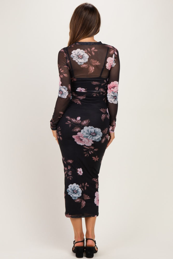 woman wearing a black floral maternity dress with long sleeves and a fitted silhouette, showing her baby bump