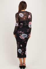 woman wearing a black floral maternity dress with long sleeves and a fitted silhouette, showing her baby bump