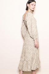 woman wearing a beige floral midi dress with puffed sleeves and a ruffled hem, shown from the side