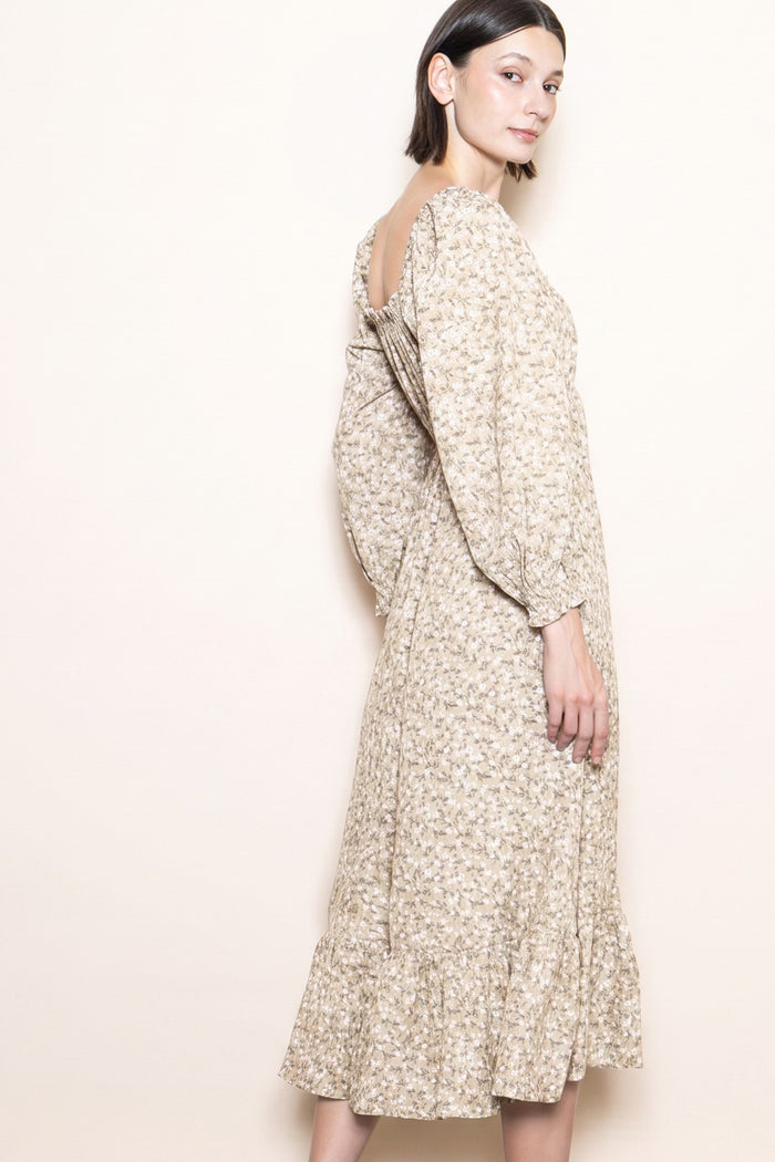 woman wearing a beige floral midi dress with puffed sleeves and a ruffled hem, shown from the side