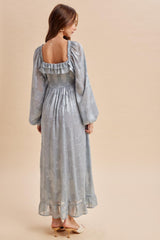 woman wearing a light blue long sleeve maxi dress with floral patterns and puffed sleeves, showing the back view