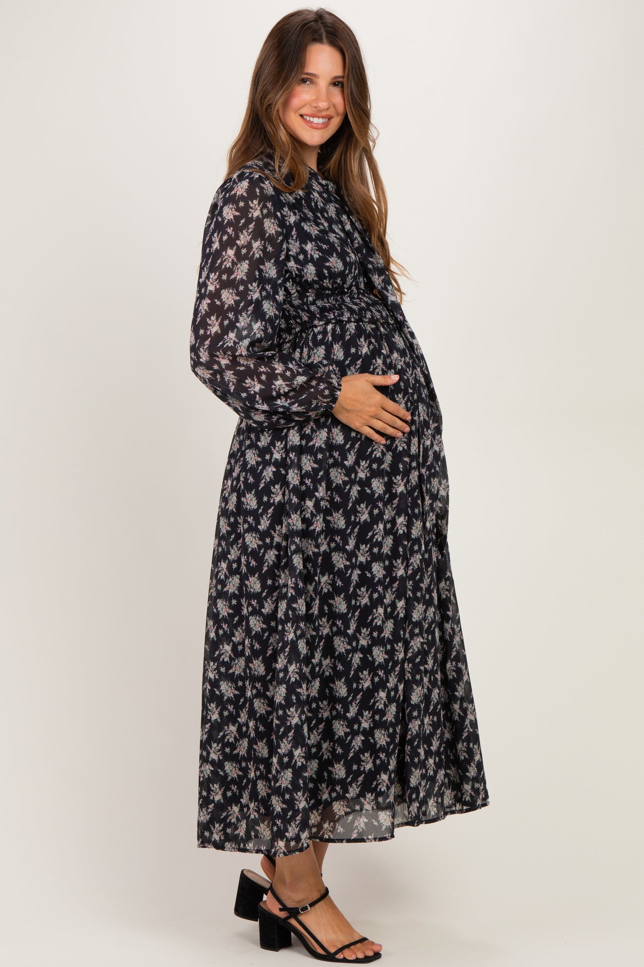 woman wearing a black floral long sleeve maternity dress and holding her baby bump