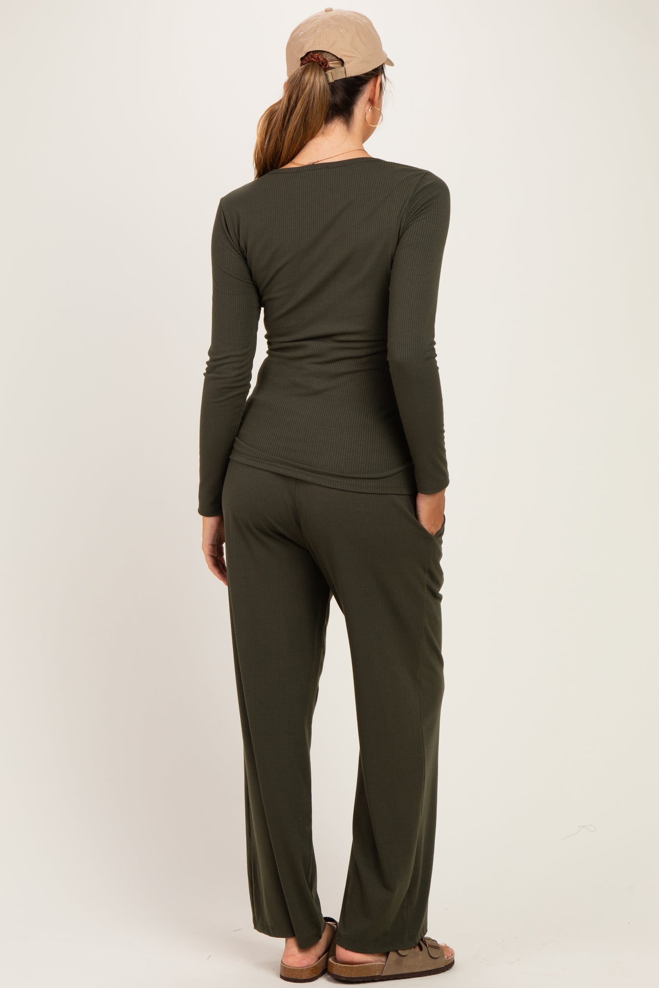 woman wearing a dark green long sleeve maternity top and matching pants, viewed from the back