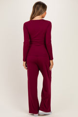 woman wearing a burgundy maternity long sleeve top and matching pants, showing a relaxed fit from the back