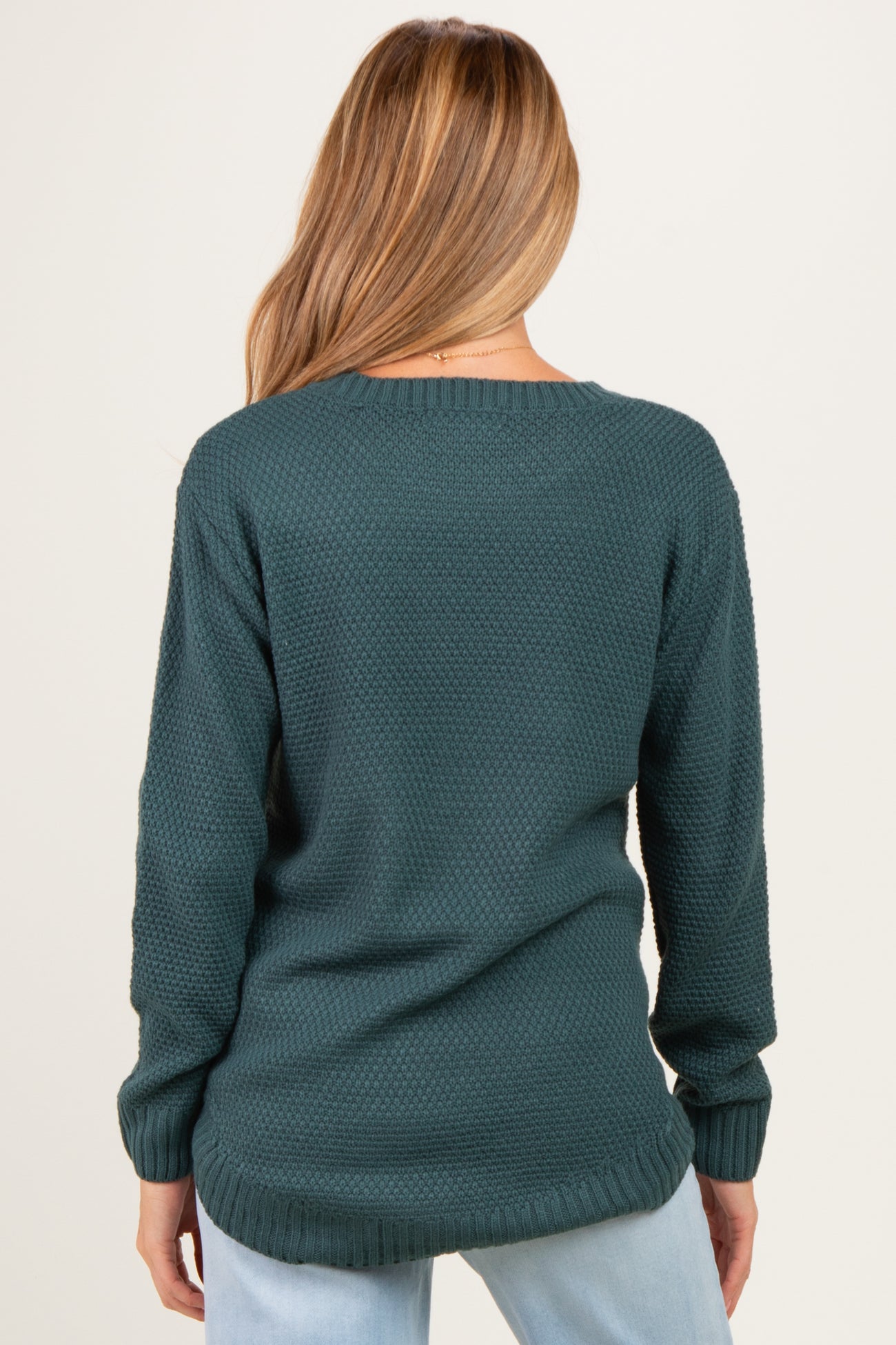 woman wearing a dark teal maternity sweater with a textured knit and relaxed fit, seen from the back
