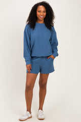 woman wearing a blue cozy sweatshirt and matching shorts, styled with white sneakers