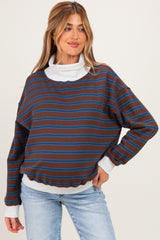 woman wearing a brown striped maternity sweatshirt with a white turtleneck underneath, styled with blue jeans