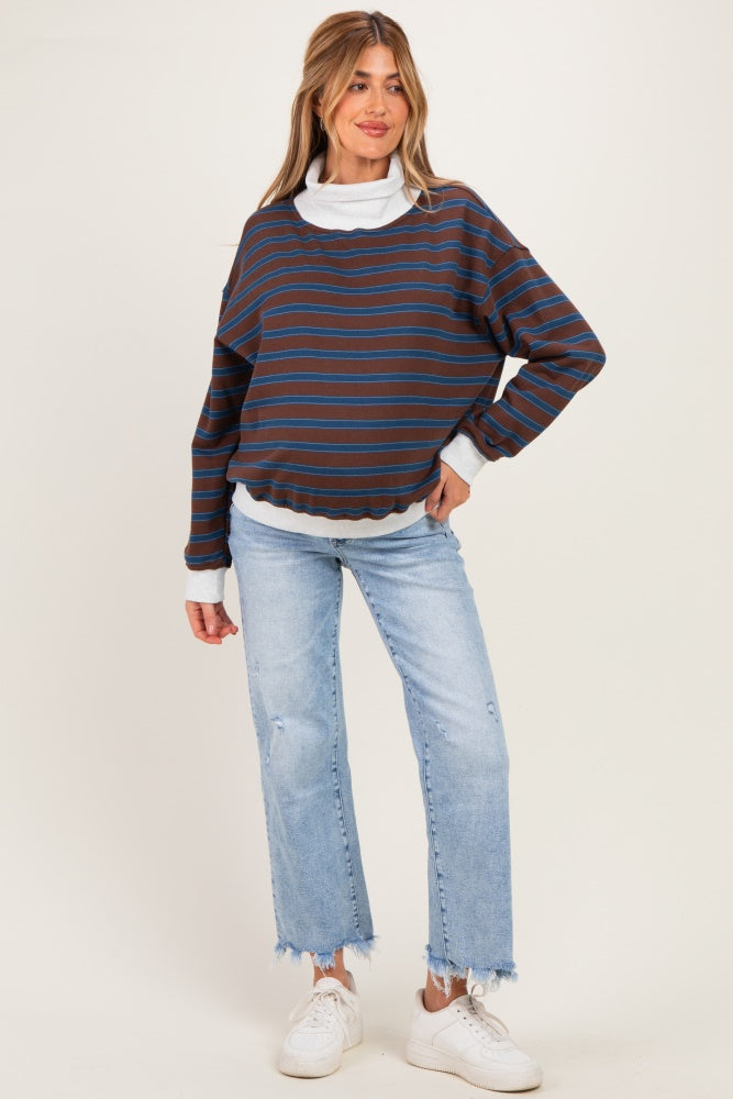 woman wearing a striped maternity sweatshirt with blue and brown tones, paired with distressed light blue jeans