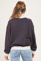 woman wearing a brown and blue striped maternity sweatshirt with a loose fit, showing a baby bump in light blue jeans