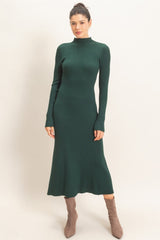 woman wearing a dark green ribbed midi dress with long sleeves and a fitted silhouette, paired with tan ankle boots