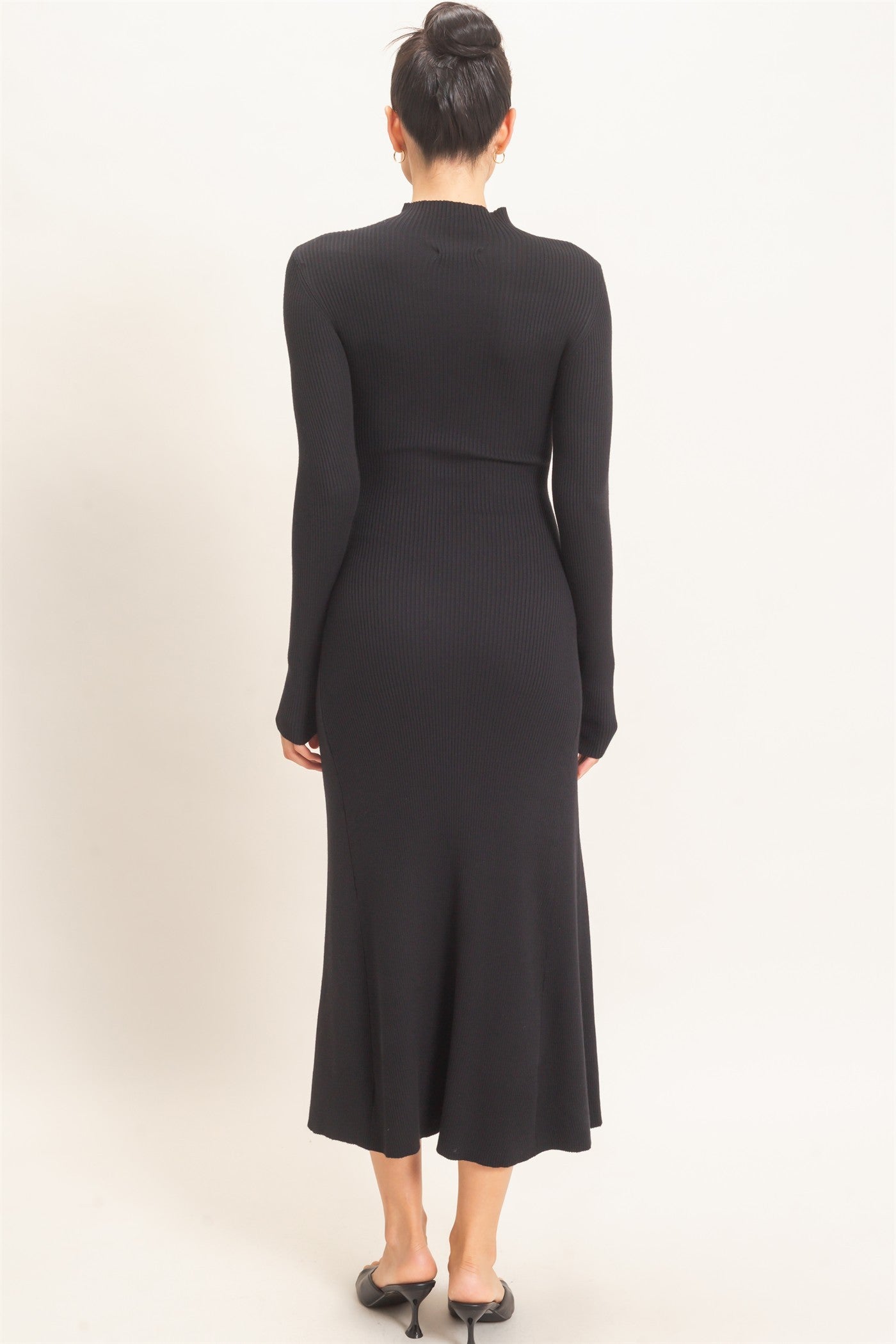 woman wearing a black ribbed long sleeve midi dress viewed from the back