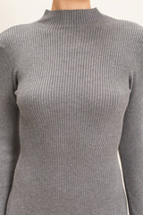 woman wearing a gray ribbed long sleeve top with a high neck design
