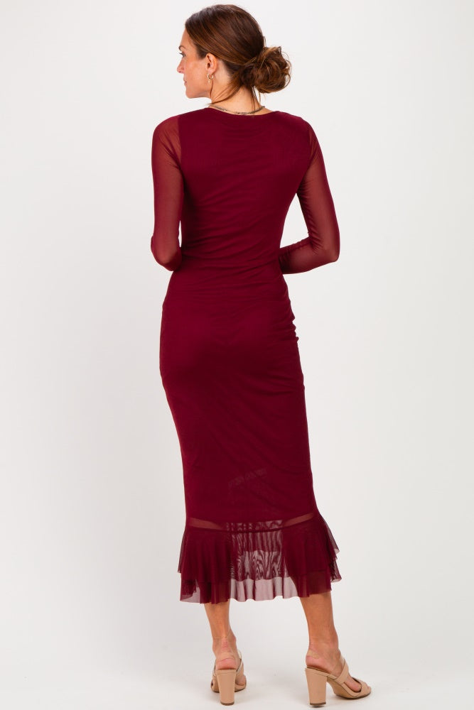 woman wearing a burgundy long sleeve dress with a ruffled hem, seen from the back