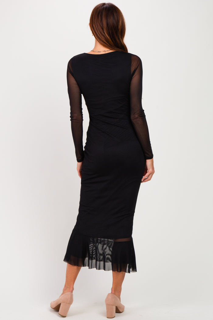 woman wearing a black long sleeve fitted dress with a sheer hem and back detailing