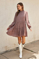 woman wearing a floral long sleeve dress in dusty rose with a pleated skirt and white cowboy boots