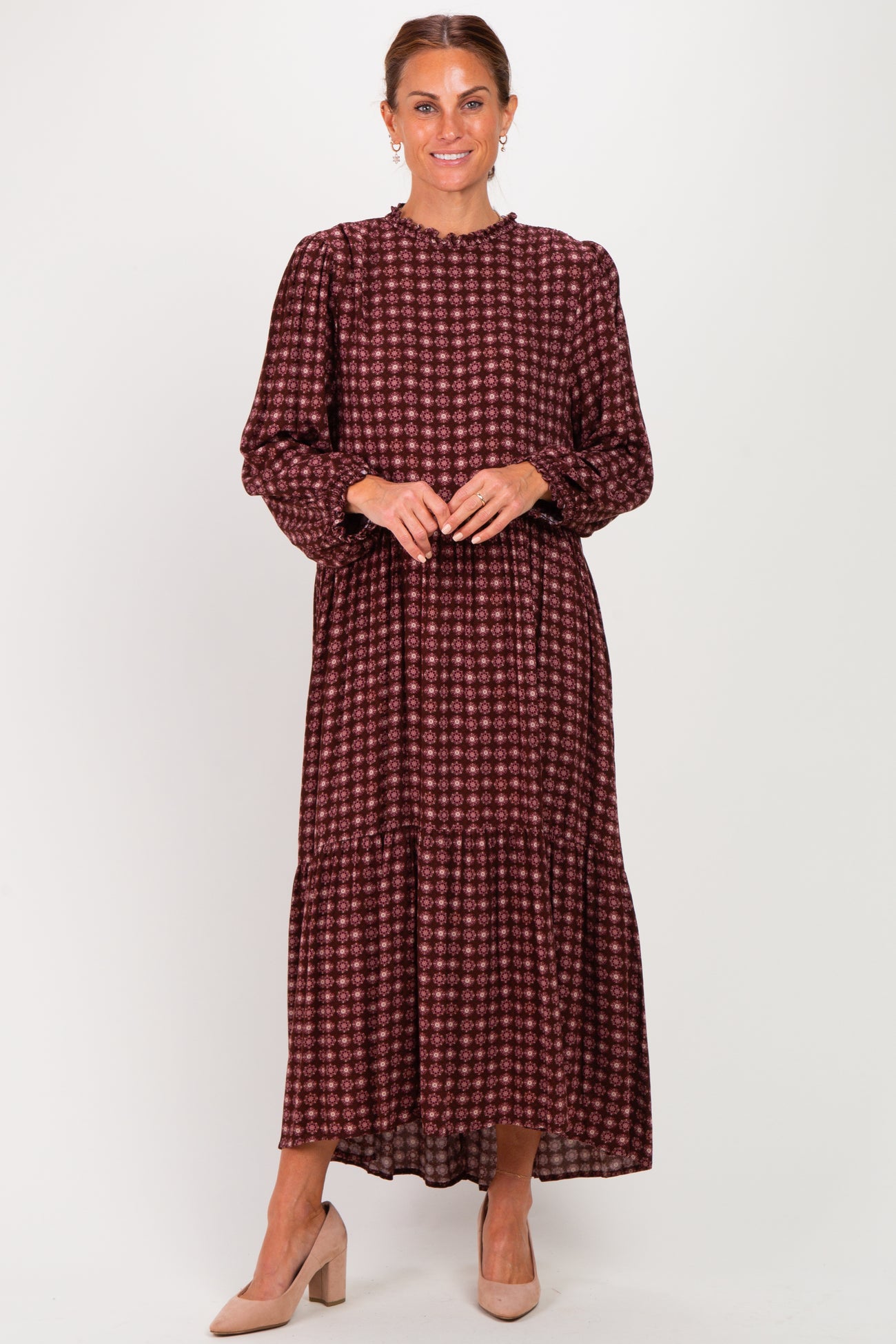 woman wearing a burgundy long sleeve tiered maxi dress with a floral pattern and ruffle neckline