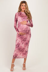 woman wearing a long pink floral maternity dress and holding her baby bump