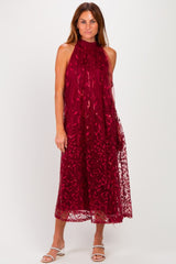 woman wearing a burgundy sleeveless dress with floral lace overlay and a flowy silhouette