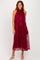 woman wearing a burgundy sleeveless dress with floral lace overlay and a flowy silhouette