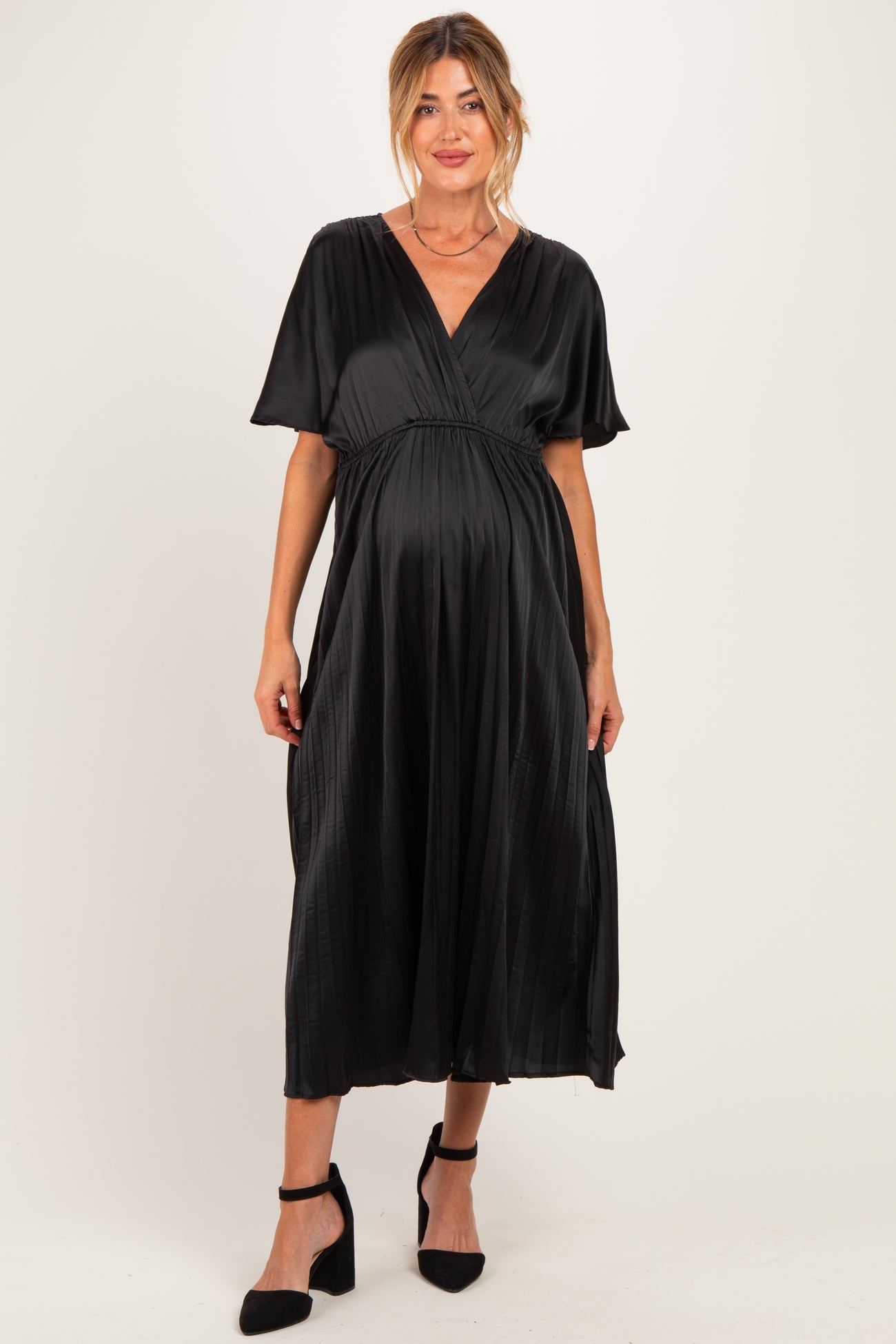 woman wearing a black maternity dress with short sleeves and a flowy skirt, showing her baby bump