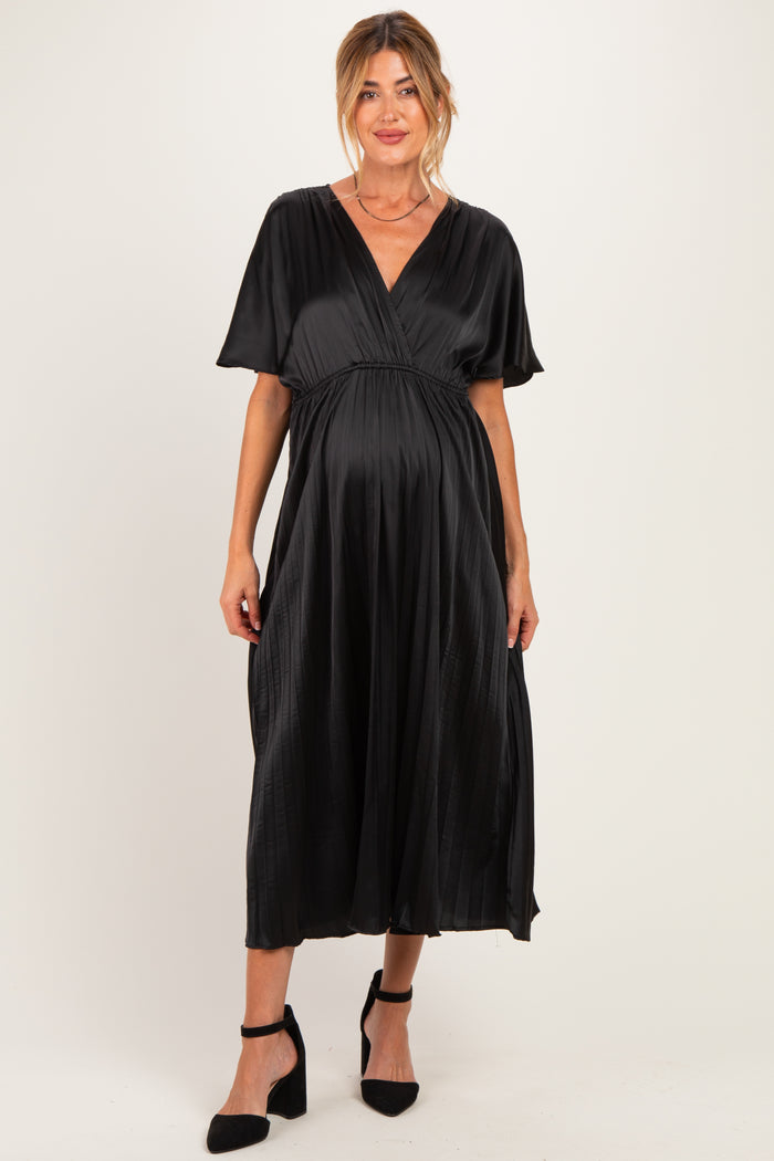 woman wearing a black maternity dress with short sleeves and a flowy skirt, showing her baby bump