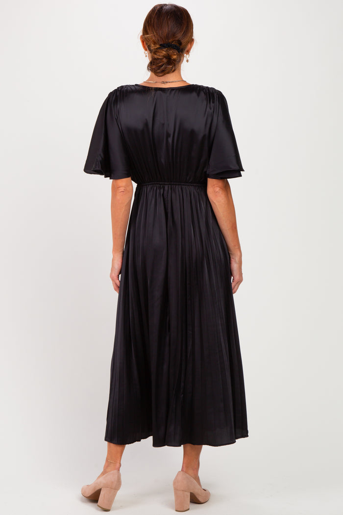 woman wearing a black pleated midi dress with a cinched waist and short sleeves, view from the back