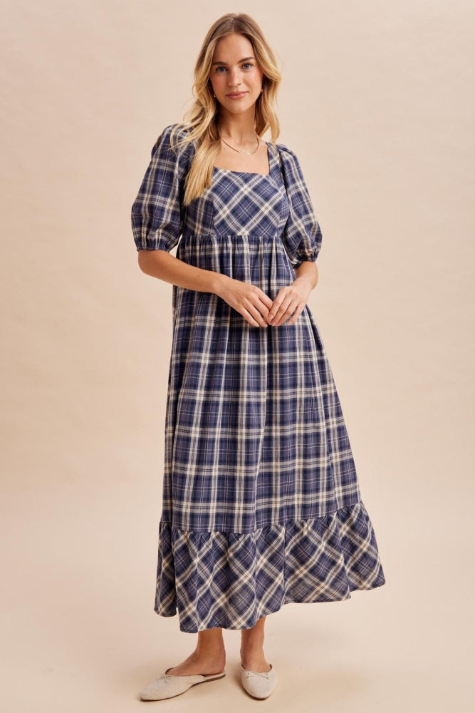 woman wearing a navy blue plaid maxi dress with puff sleeves and a ruffled hem