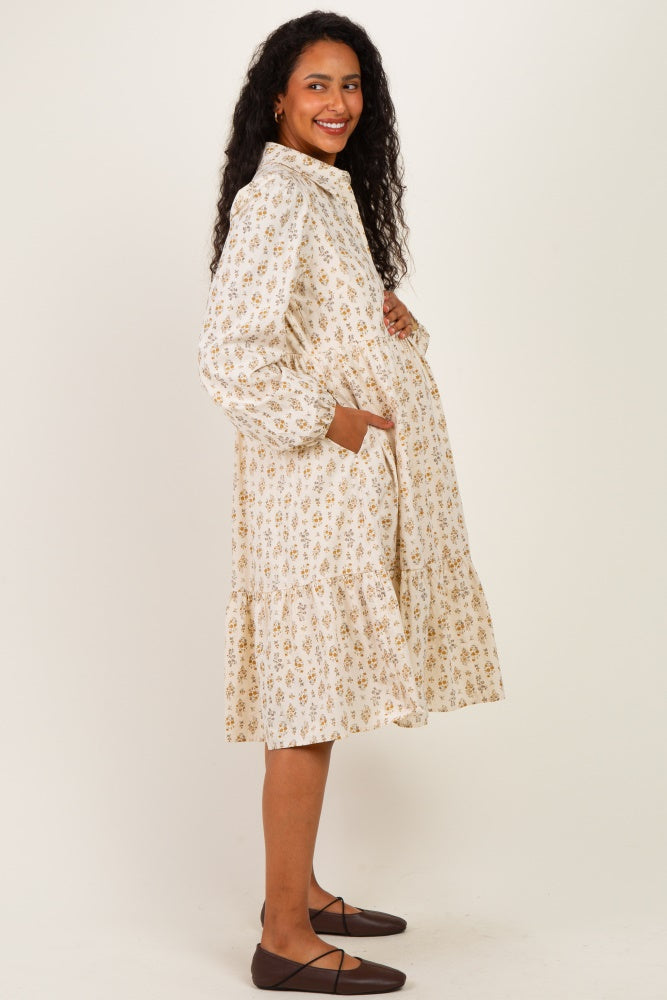 woman wearing a floral patterned maternity dress with pockets, featuring a tiered skirt and long sleeves, smiling