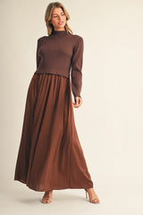woman wearing a brown ribbed sweater and a flowing brown maxi skirt, standing elegantly against a neutral background
