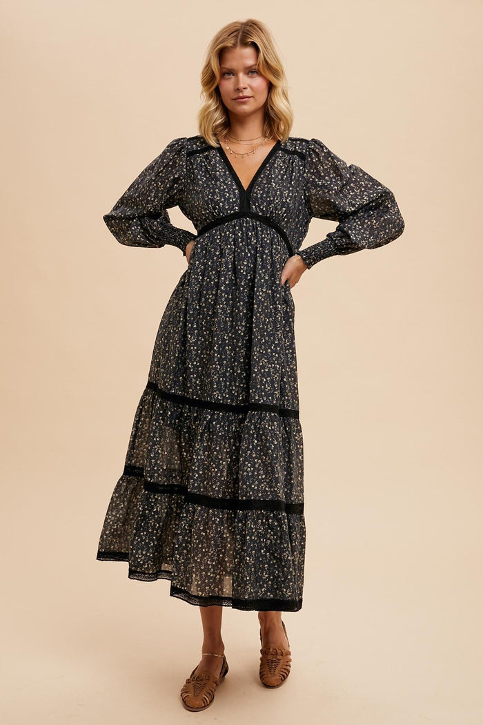 woman wearing a black floral print maxi dress with puff sleeves and tiered skirt