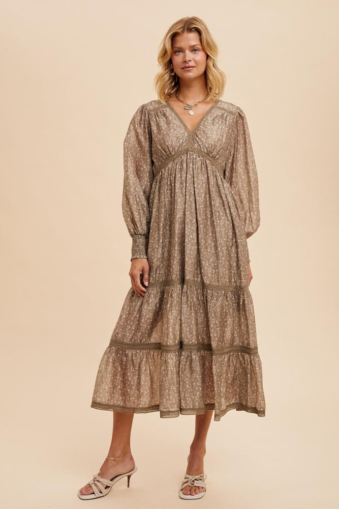 woman wearing a taupe floral maxi dress with puff sleeves and tiered skirt