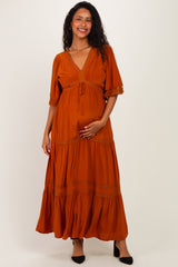 woman wearing an orange maternity maxi dress with a v-neck, short sleeves, and holding her baby bump